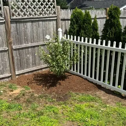 Freshly planted bed beside a white picket fence