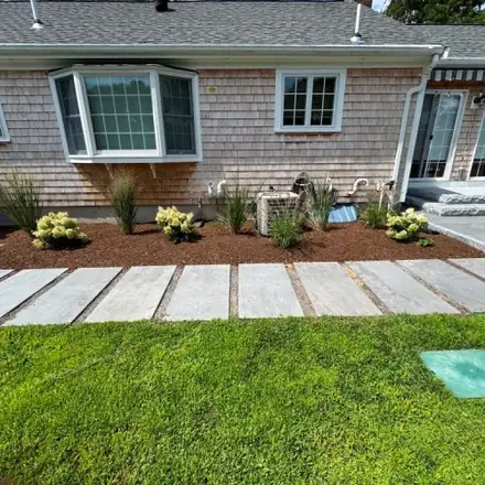Stone walkway and planting bed along a Cape home
