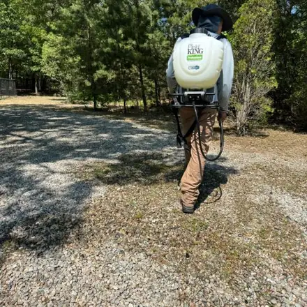 Crew member spraying a gravel area